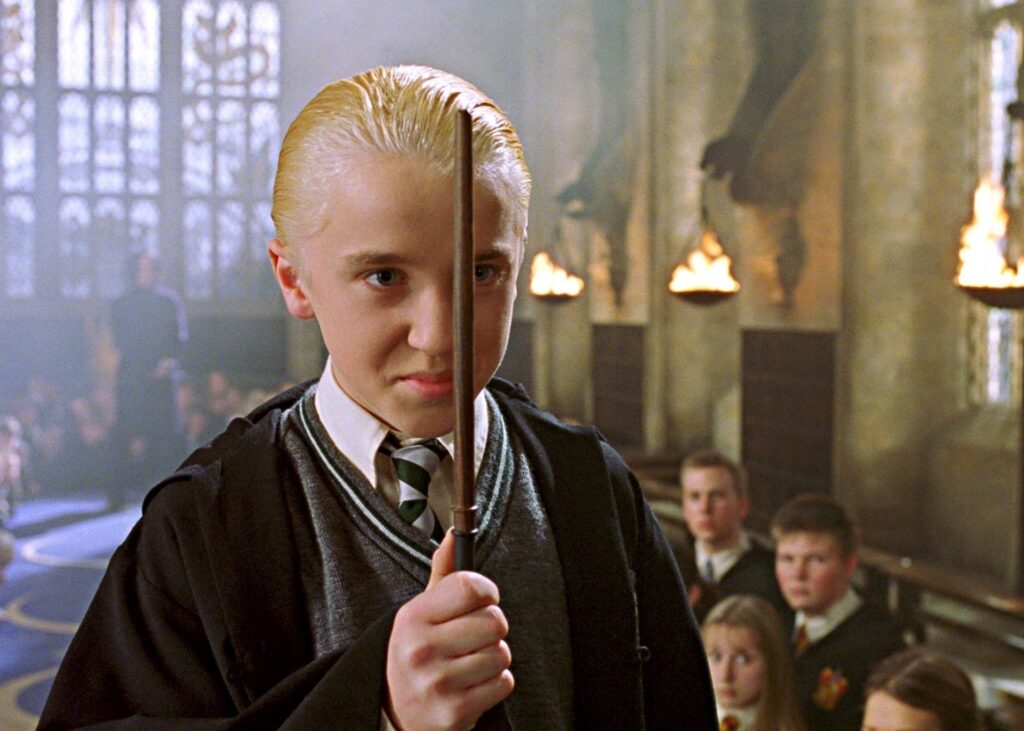 Draco Malfoy looking menacing while holding his wand in Harry Potter.